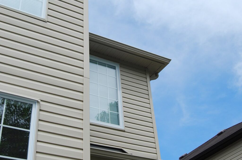 Beige vinyl siding with white windows on a two-story home under a blue sky
