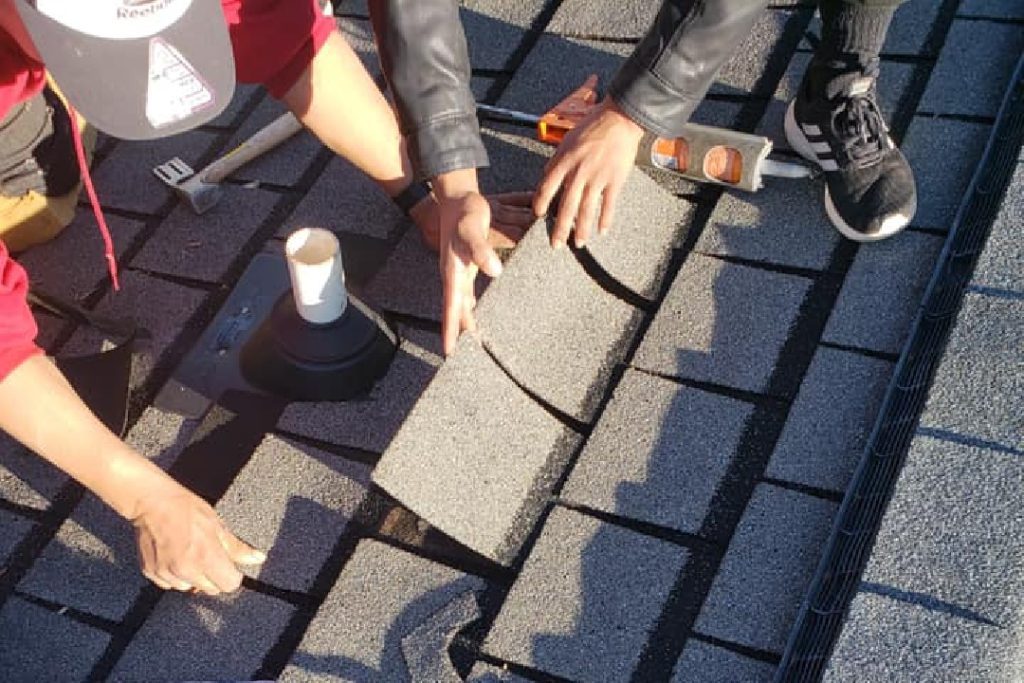 Roofer inspecting shingles on a Charlotte-area home before winter